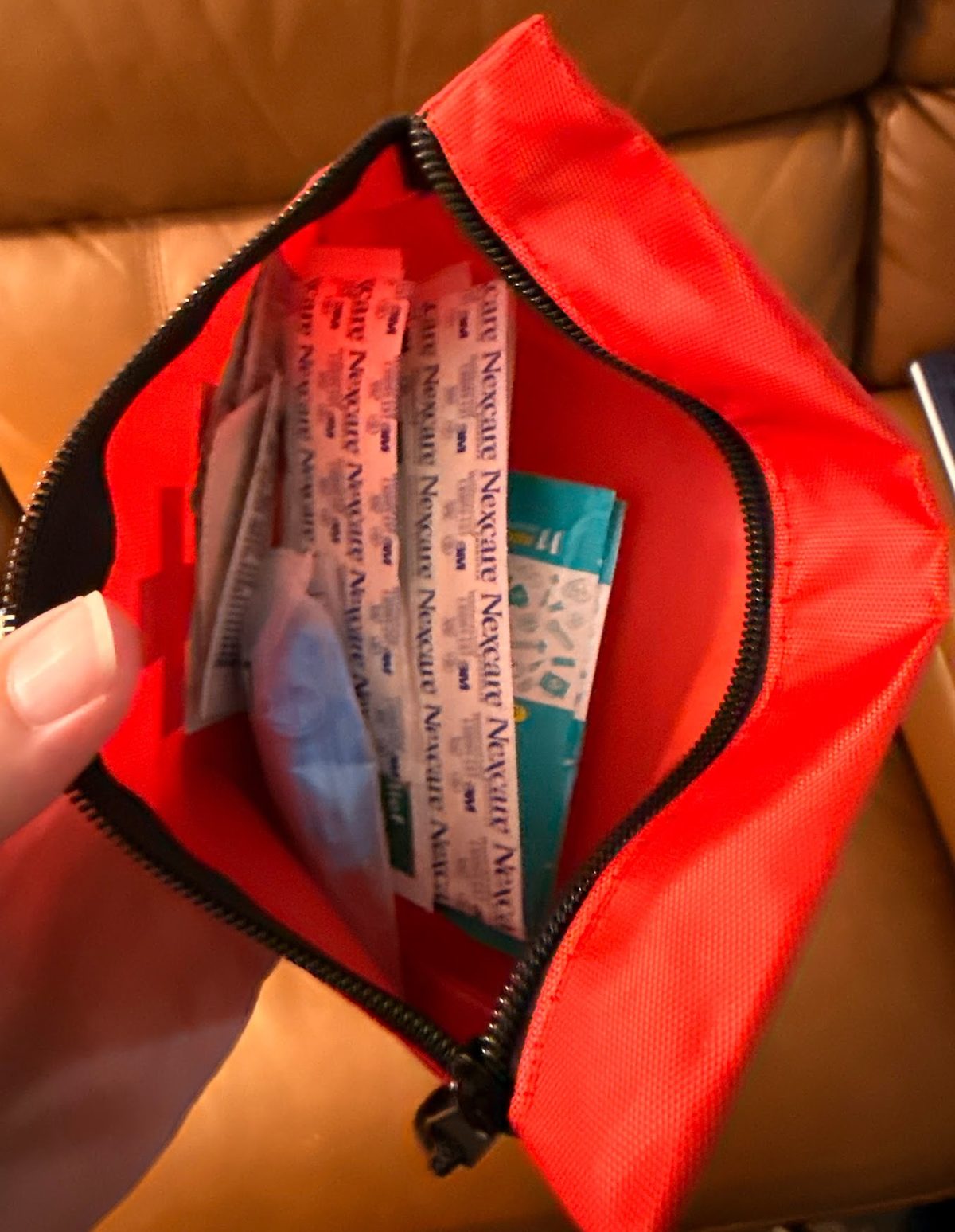 Open red zippered pouch containing several packets labeled “Nexcare.”